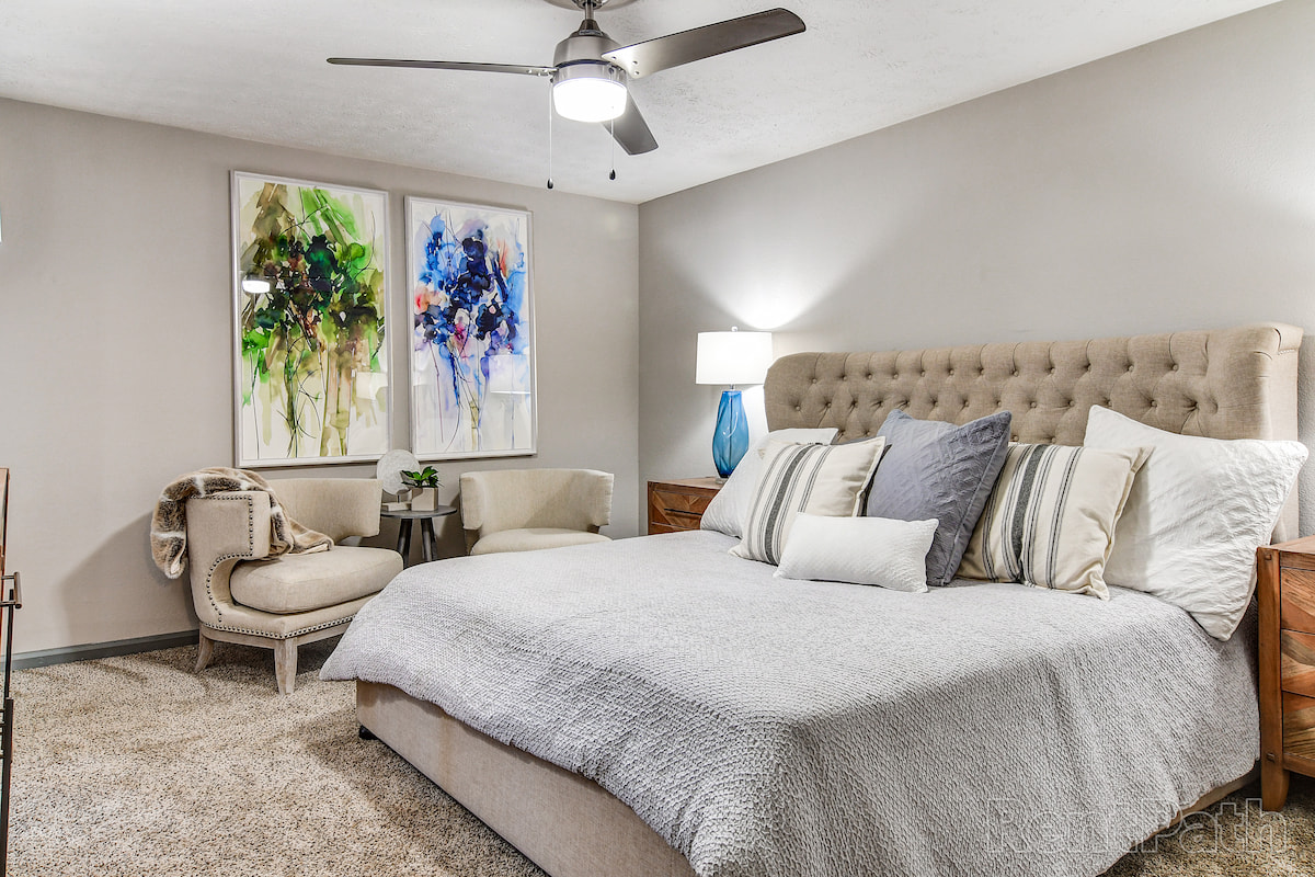 bedroom with modern furniture, ceiling fan and wall art
